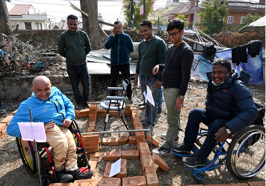 Deepak Khatri Chhetri and a group of other people around a pile of bricks well layed out. 