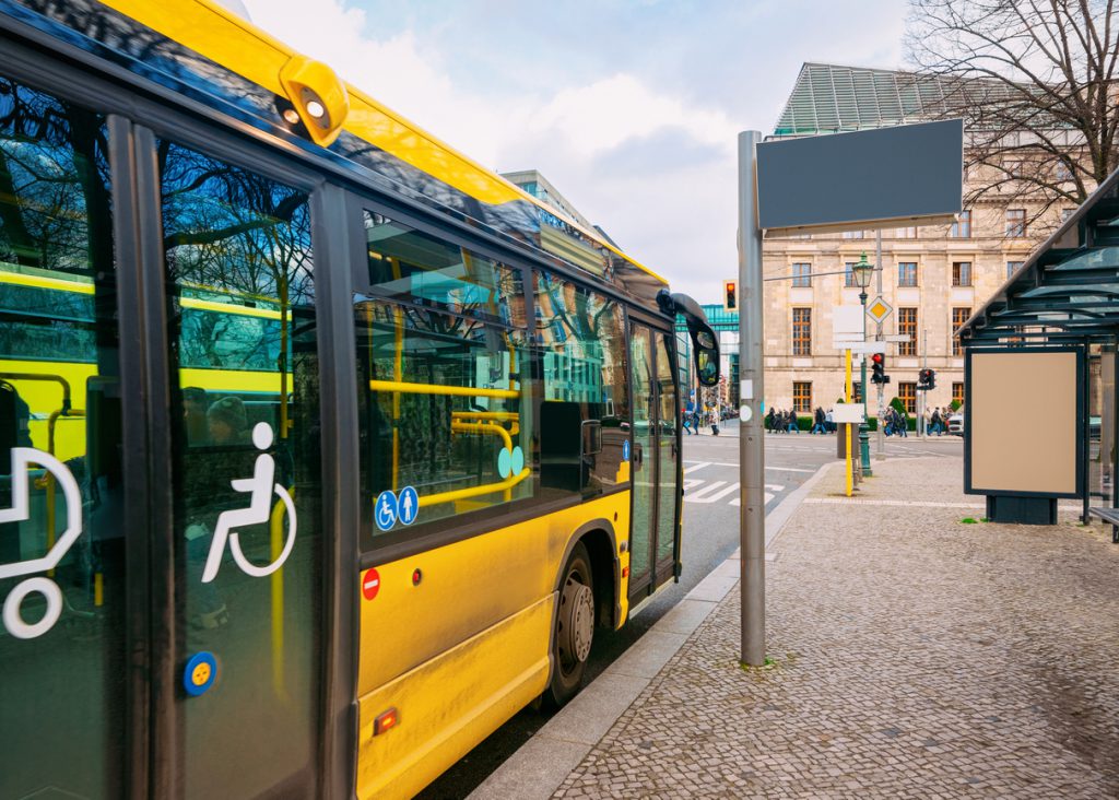 Yellow public bus with entrance door for people with disability at the bus stop in Berlin Mitte in City centre. Street in Germany in Europe. (Yellow public bus with entrance door for people with disability at the bus stop in Berlin Mitte in City centre