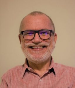 A photo of a smiling man in glasses wearing a beard and mustache
